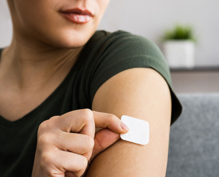 A woman is sticking cbd patch on her arm
